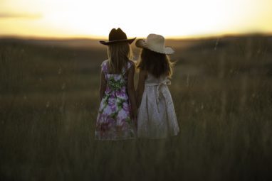 Girls with cowboy hats in field