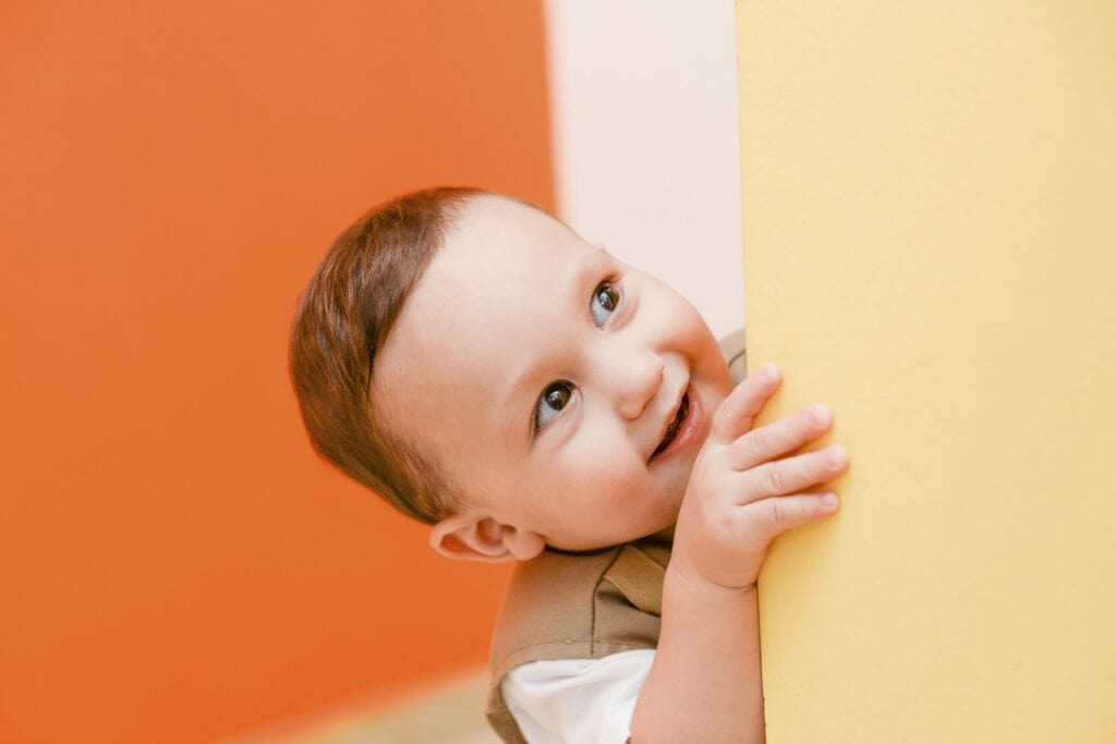 toddler boy looking around the corner